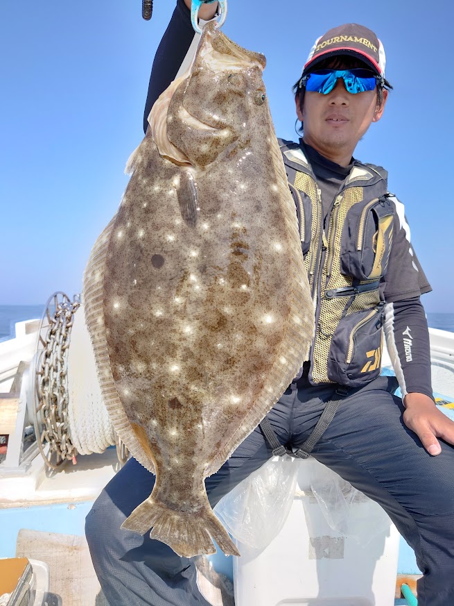船釣りで釣り上げた大型ヒラメを持つ釣り人
